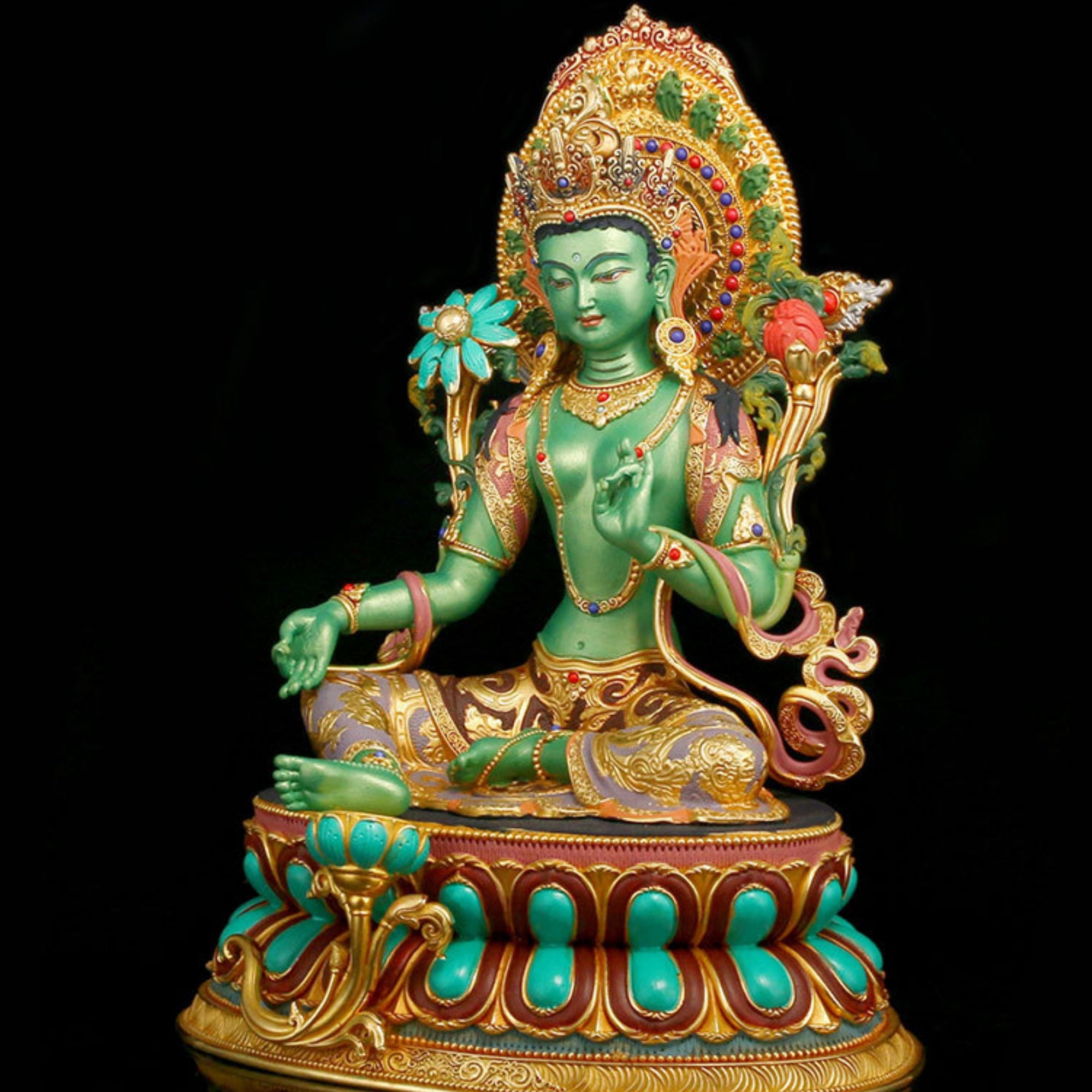 A green seated deity statue with ornate gold detailing, turquoise accents, and a jeweled halo, photographed against a solid black background.