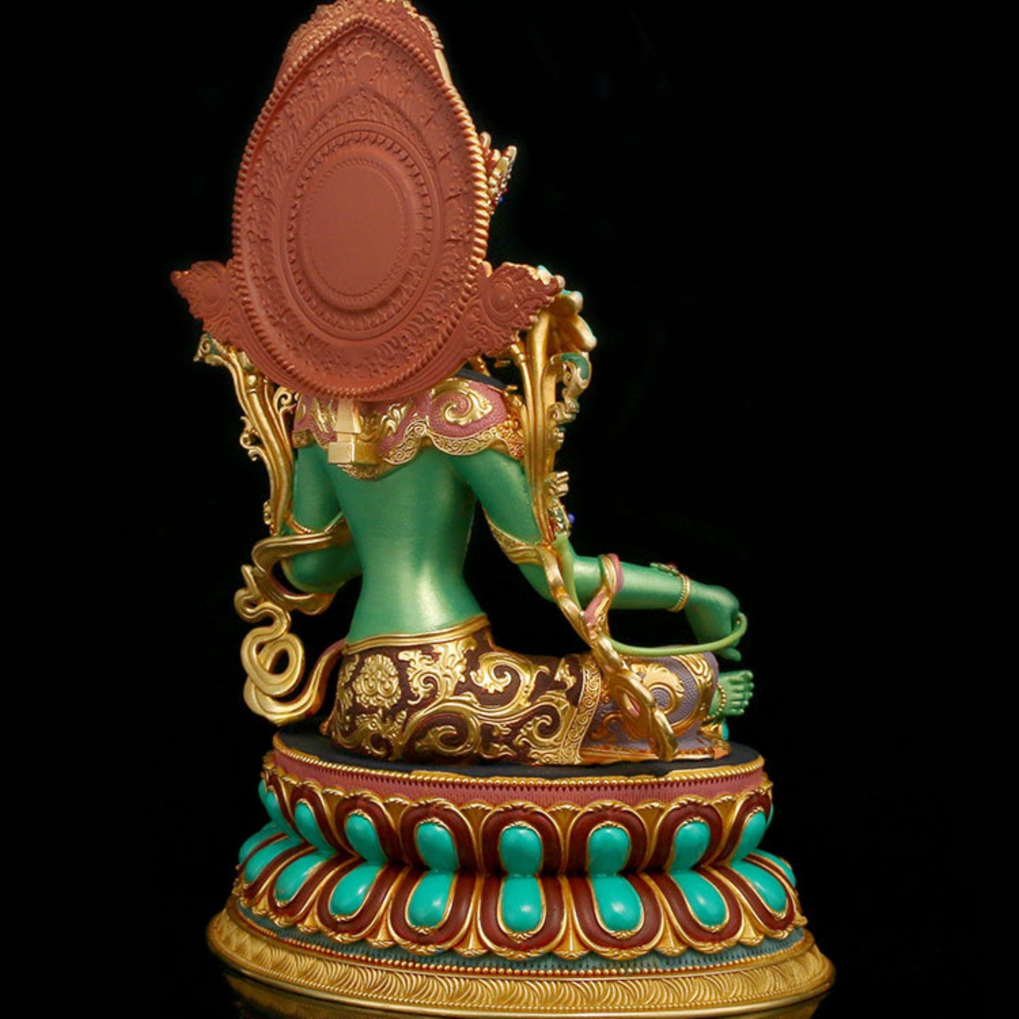 A colorful Tibetan Buddhist deity statue shown from the back, featuring a green-skinned figure with gold ornaments, a large reddish-brown circular headdress, and a turquoise and gold lotus base against a black background.