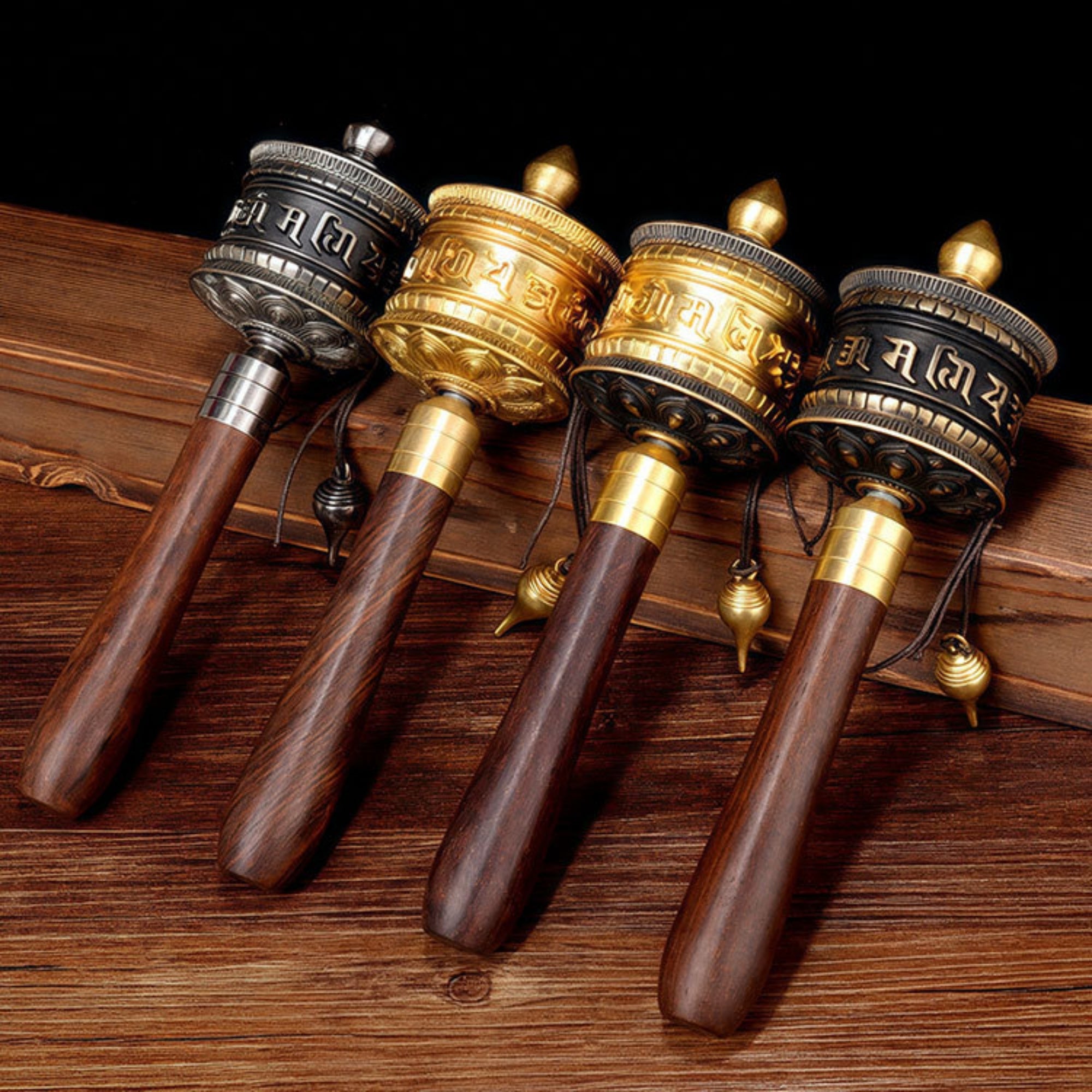 Four prayer wheels with wooden handles on a wooden surface