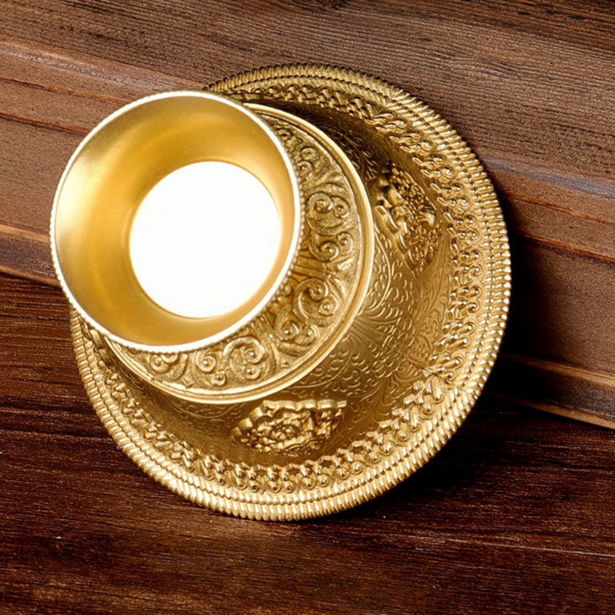 Decorative gold circular object with intricate patterns on a wooden surface