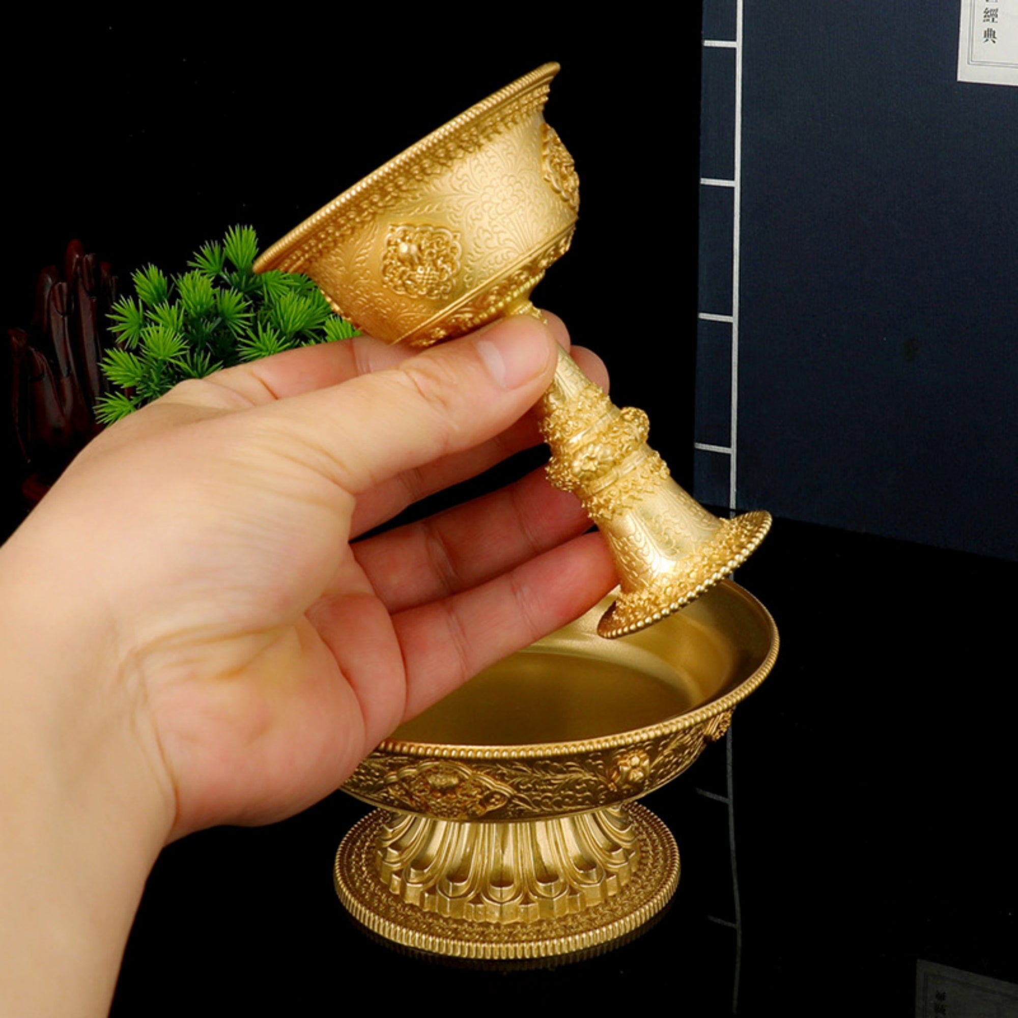 Hand holding a gold decorative object against a dark background