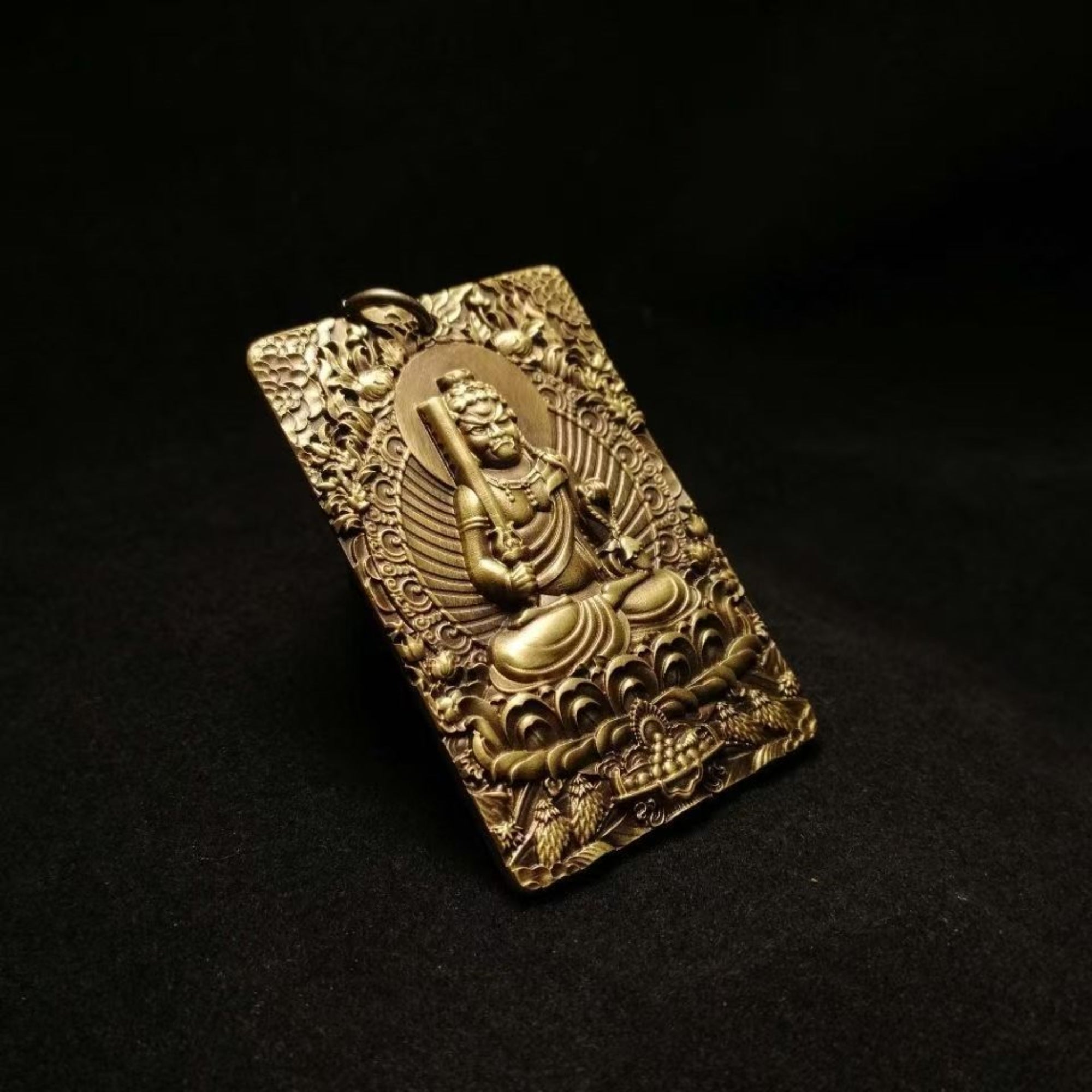 Bronze pendant with Buddha figure on a black background