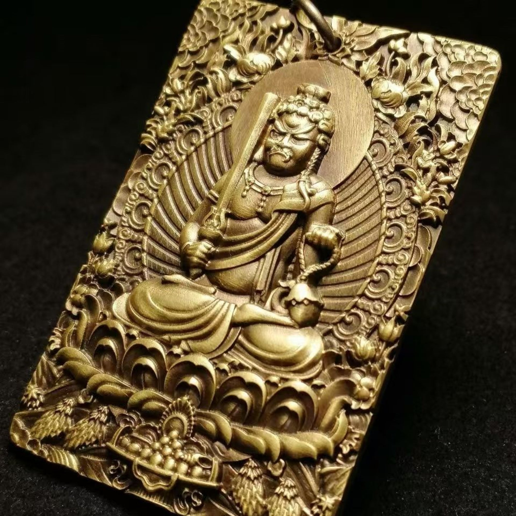 Gold-colored religious figure pendant with intricate designs on a black background