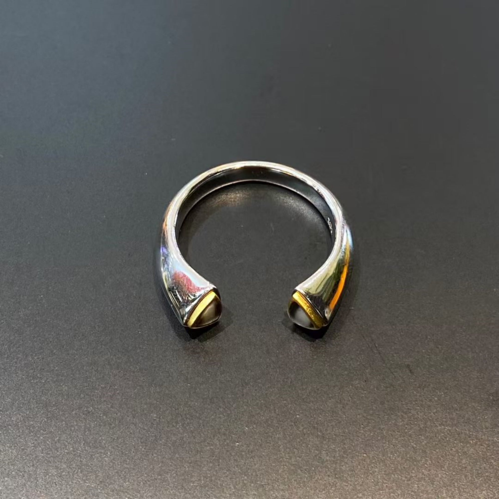 Silver bracelet with gold accents on a dark gray background