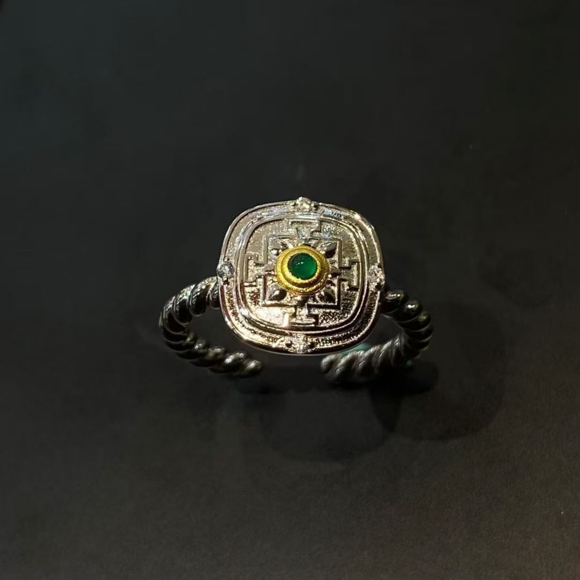 Silver ring with green gemstone on a black background