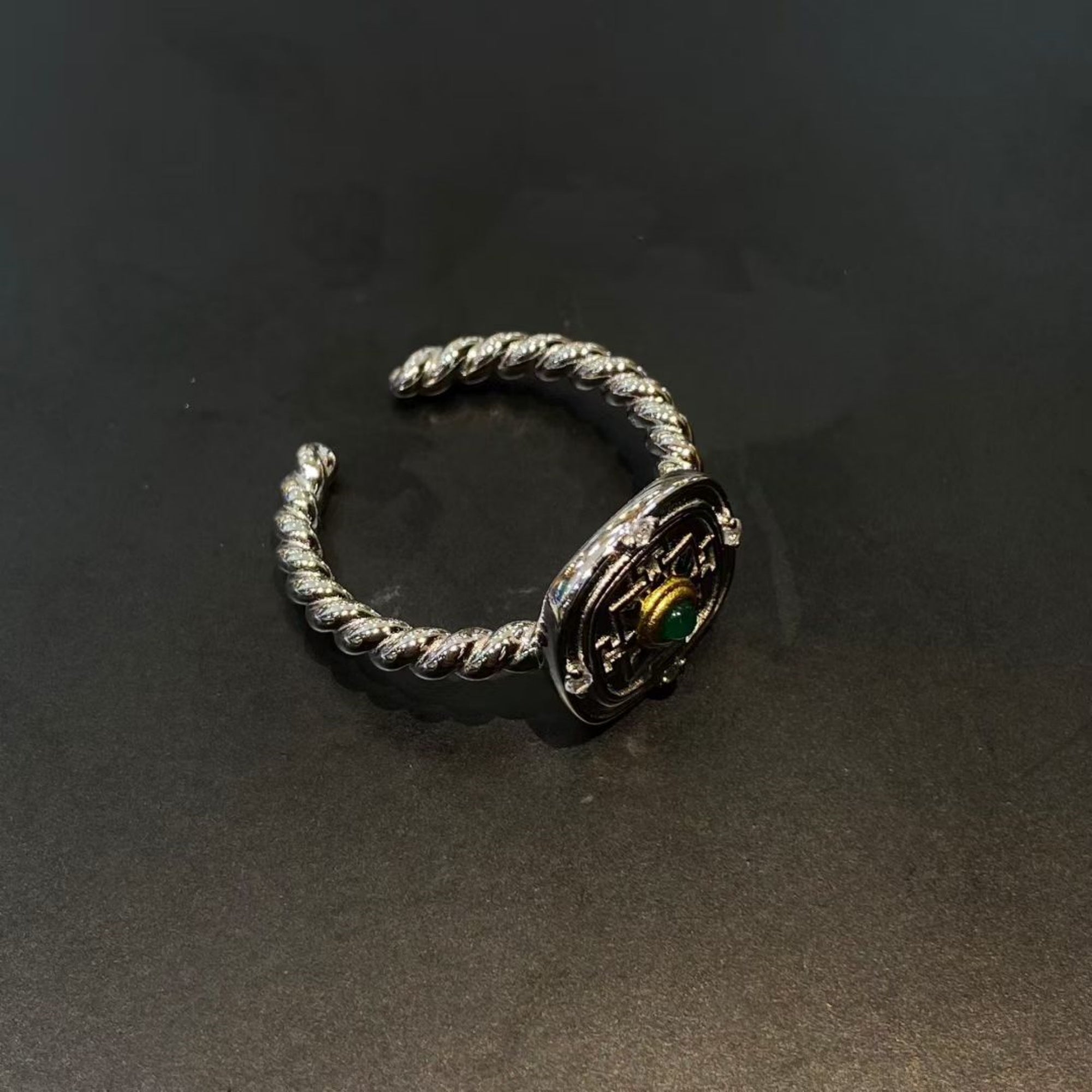Silver ring with intricate design on a dark background