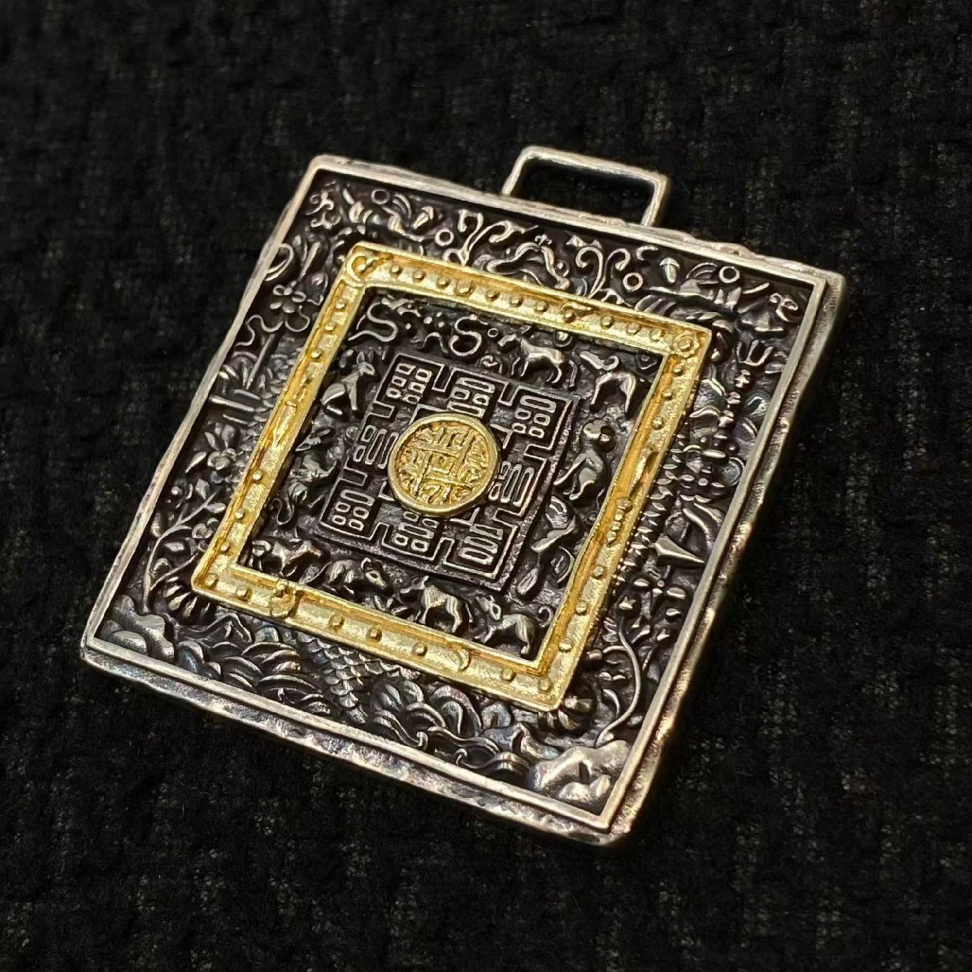 Decorative square object with gold and silver design on a black background