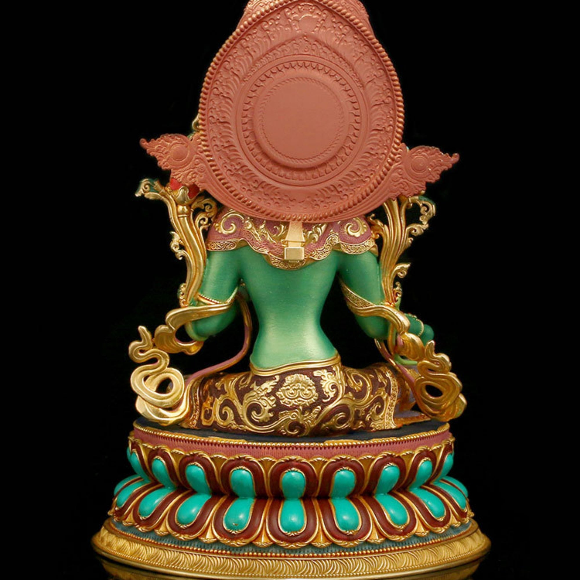 A detailed, ornate statue of a seated figure viewed from the back, featuring a green torso, gold filigree details, turquoise accents on the lotus base, and a large terracotta-colored circular element on the back, set against a solid black background.