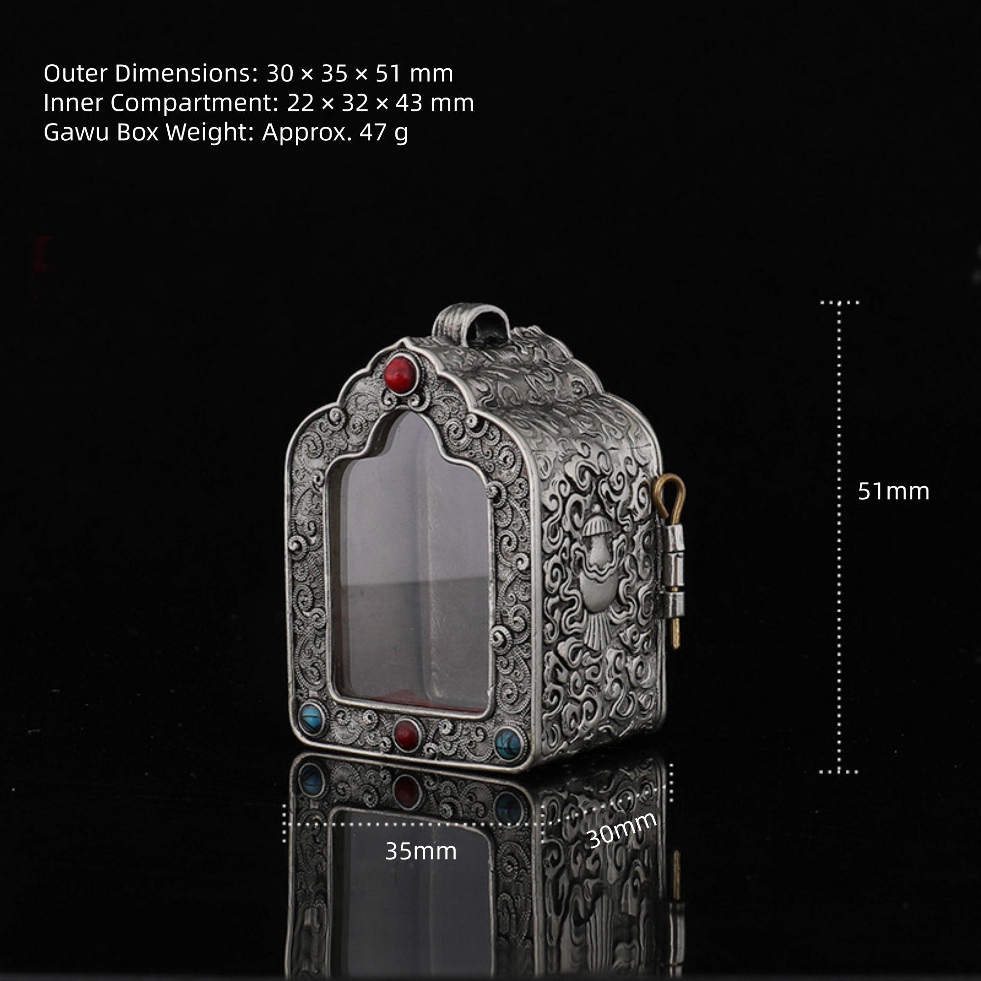 An ornate silver-toned metal Gawu box with engraved floral patterns, a clear front window, and small red and blue gemstone accents, shown on a black reflective background with printed dimensions and weight text.