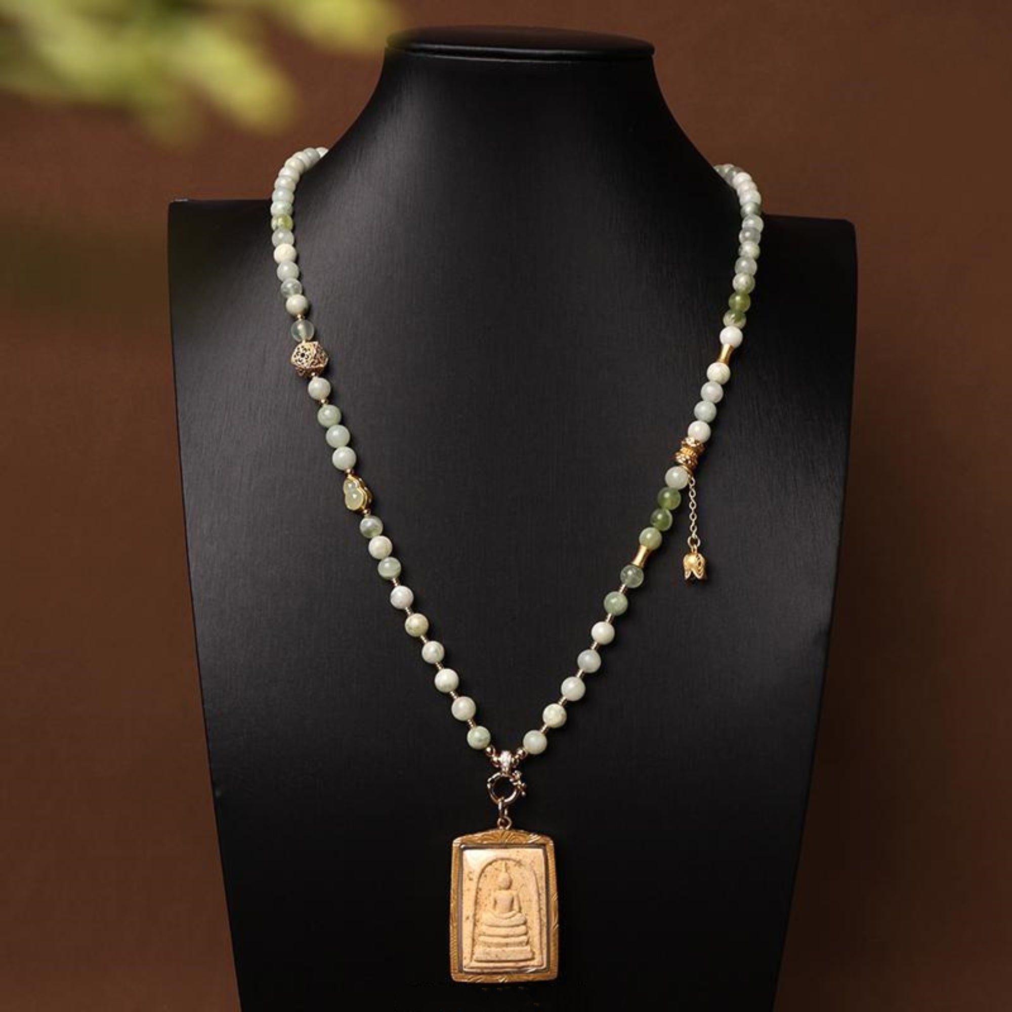 Necklace with beads and a pendant on a black mannequin against a brown background