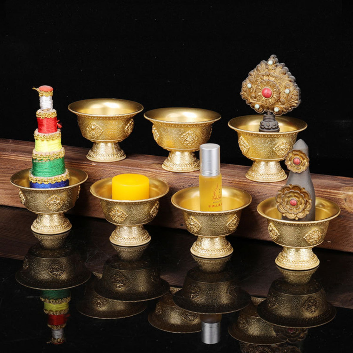 Set of gold-colored bowls with various items on a reflective surface