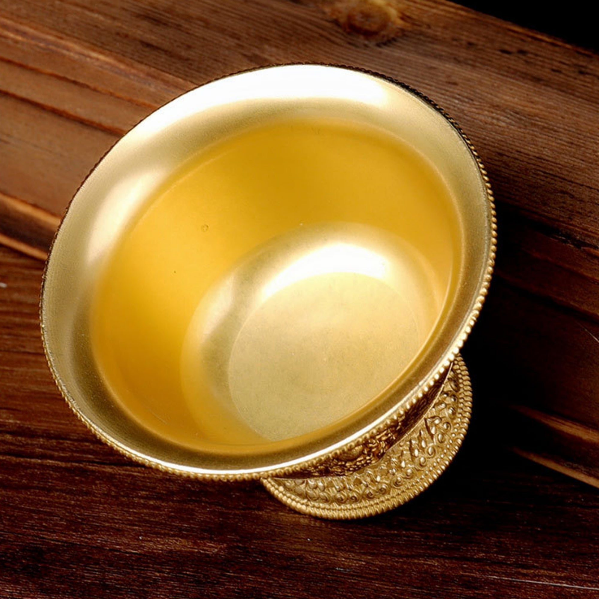 Gold cup with yellow liquid on a wooden surface