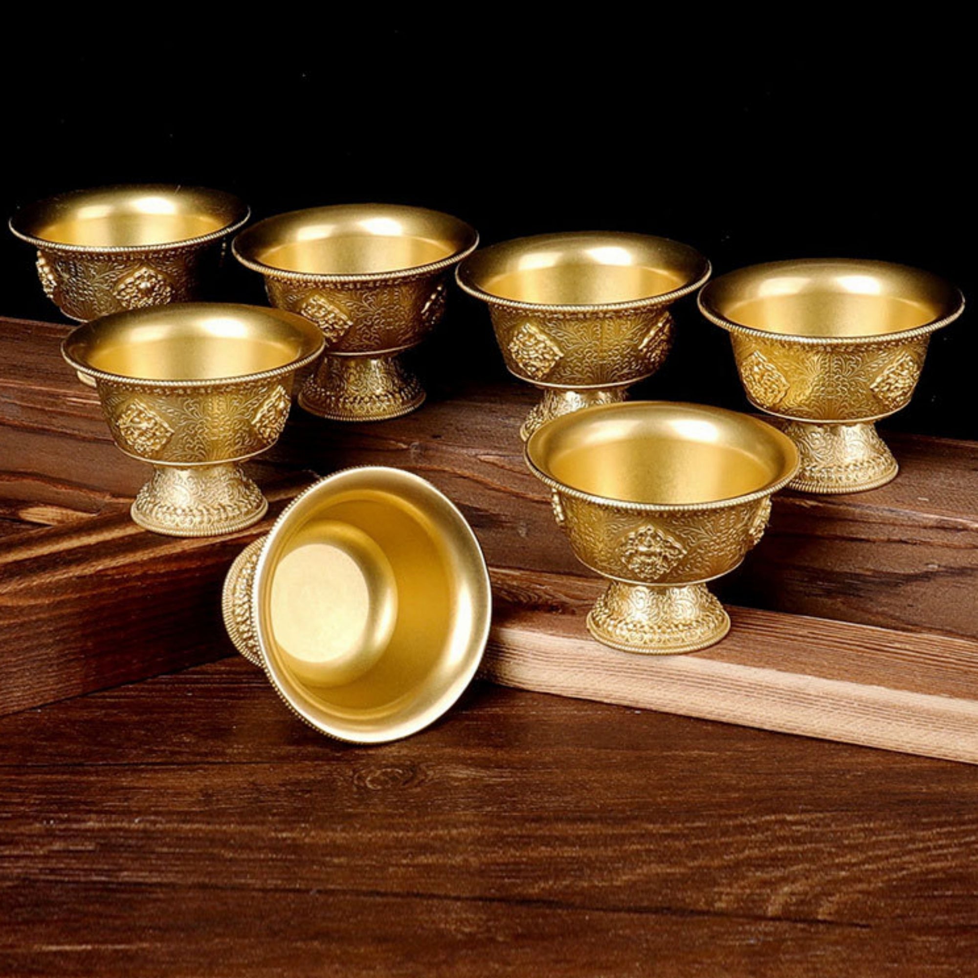 Set of gold ornate cups on a wooden surface