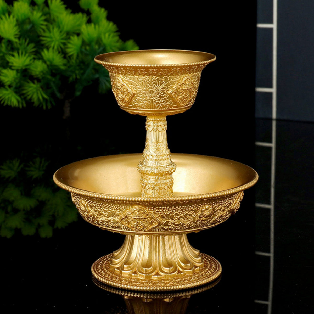 Gold ornate bowl with intricate designs on a reflective surface.
