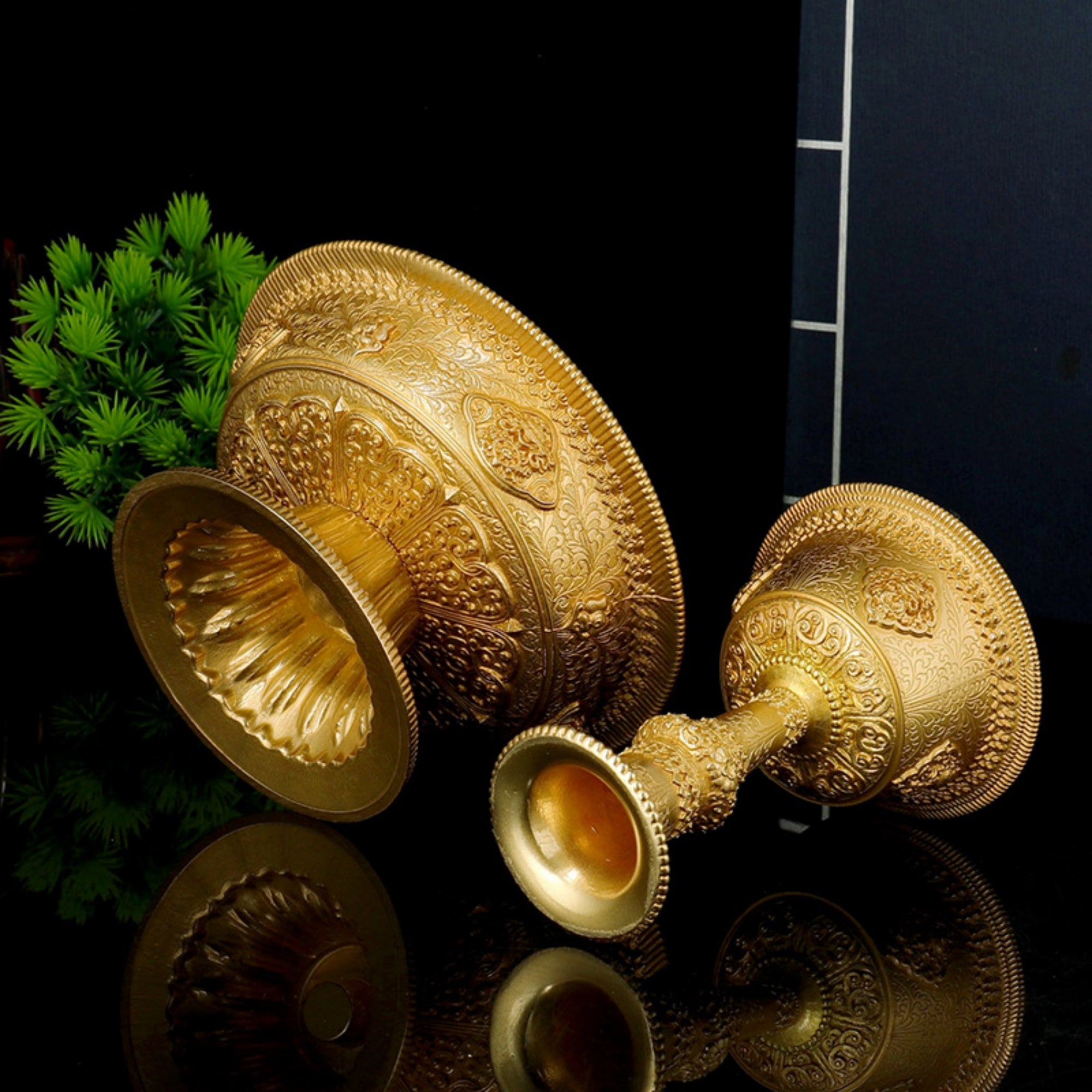 Decorative gold lamp with intricate designs on a reflective surface.