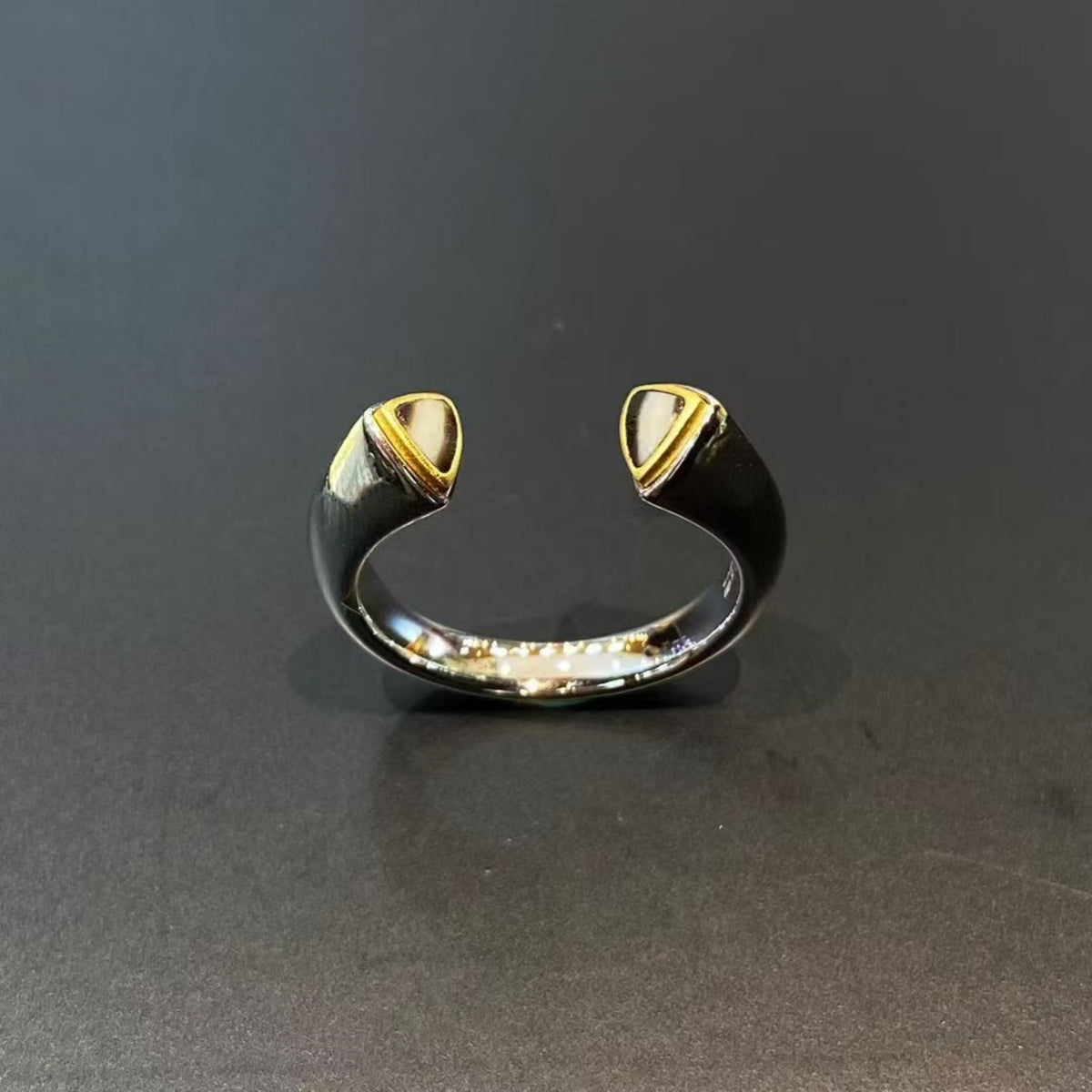 Gold and black open ring on a dark gray background