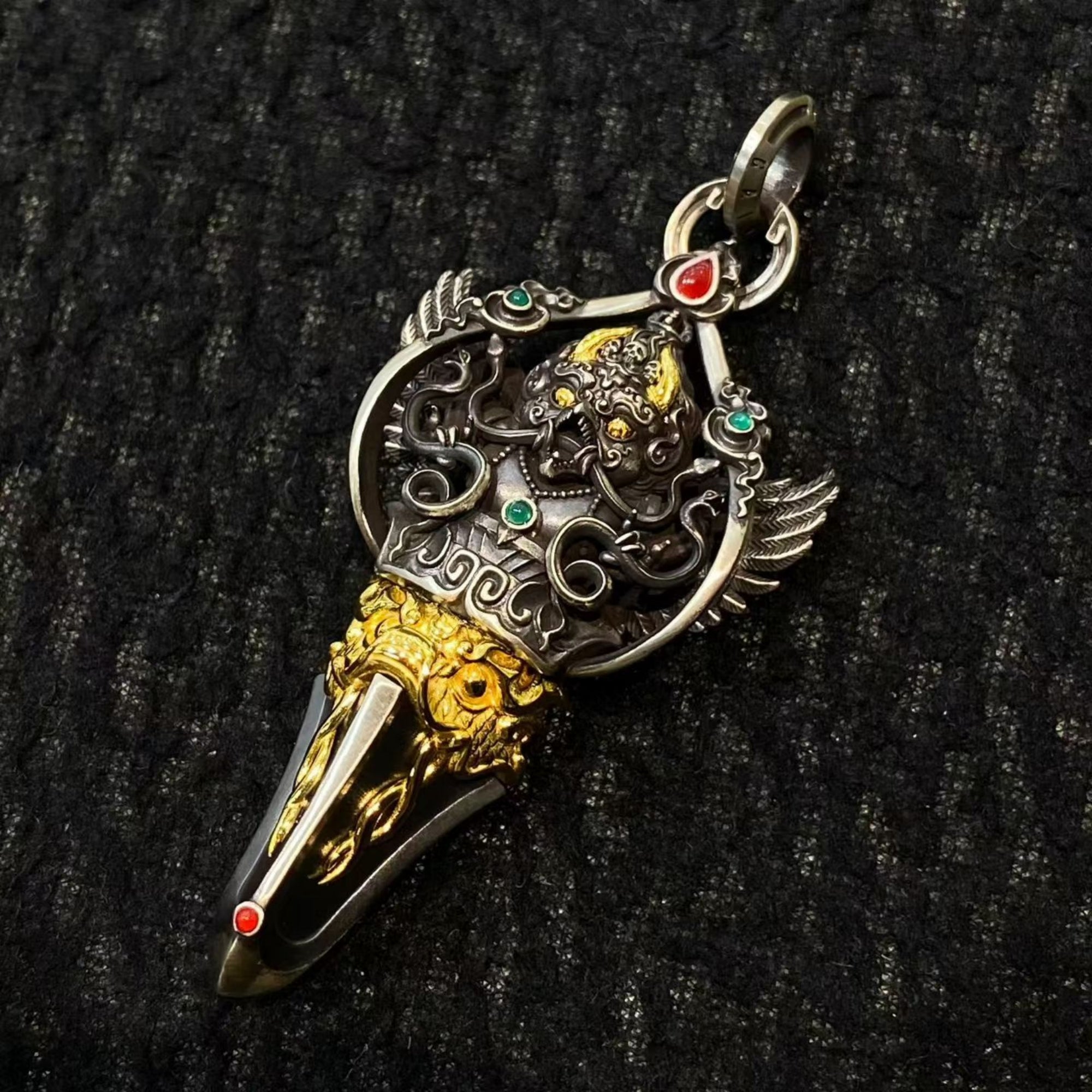 Decorative pendant with gold and silver design on a black textured background