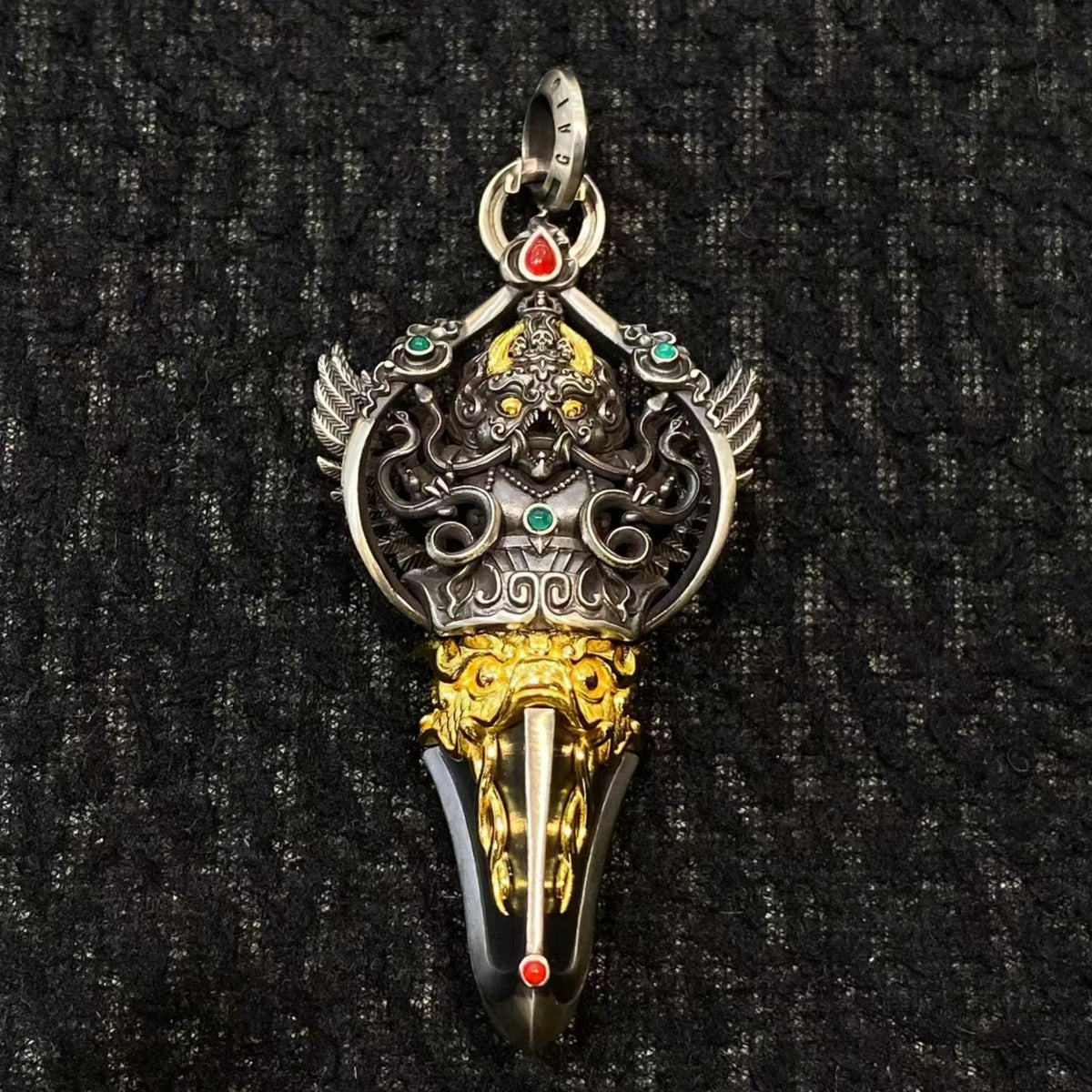 Decorative pendant with intricate designs on a black textured background