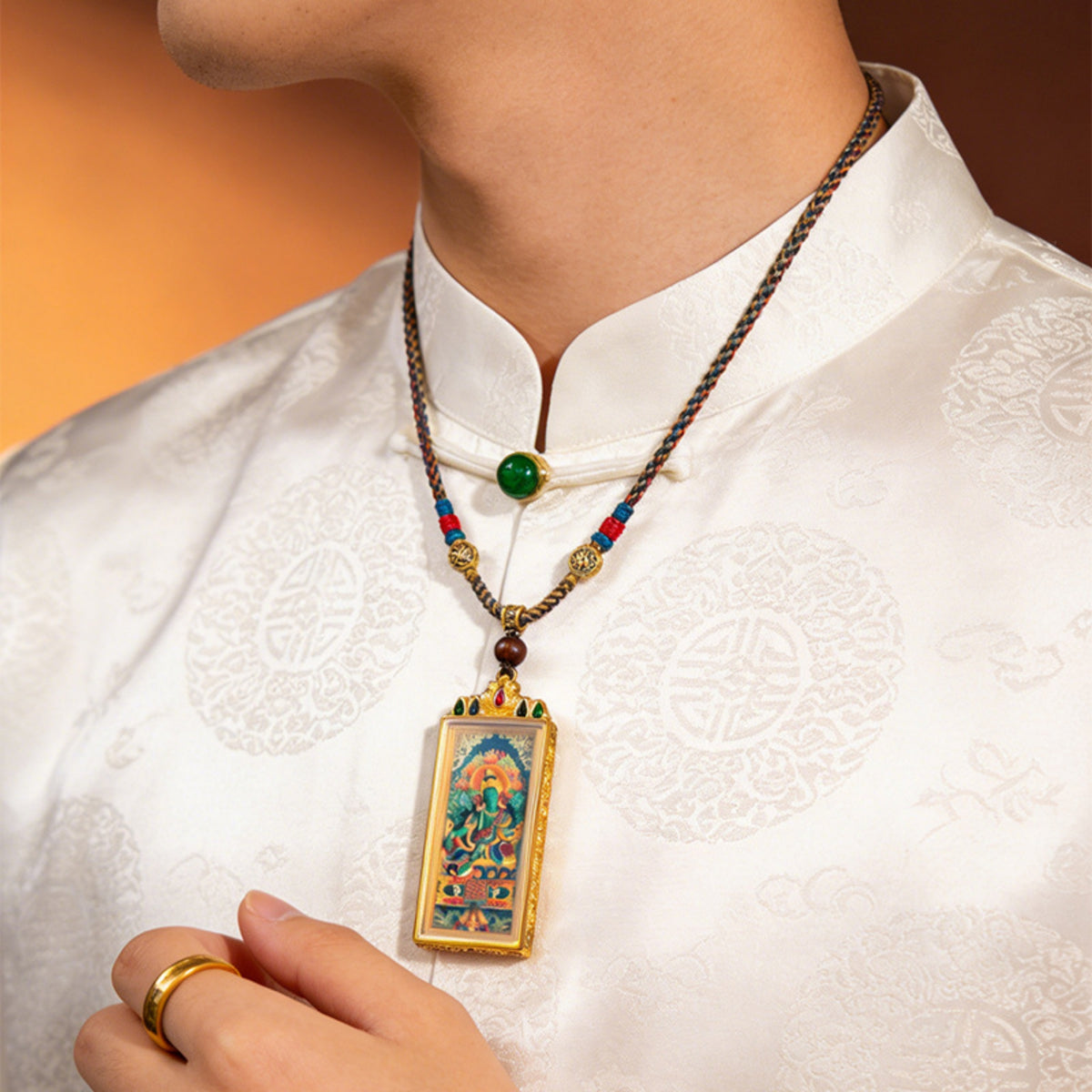 Person wearing a colorful necklace with a detailed pendant on a white shirt.