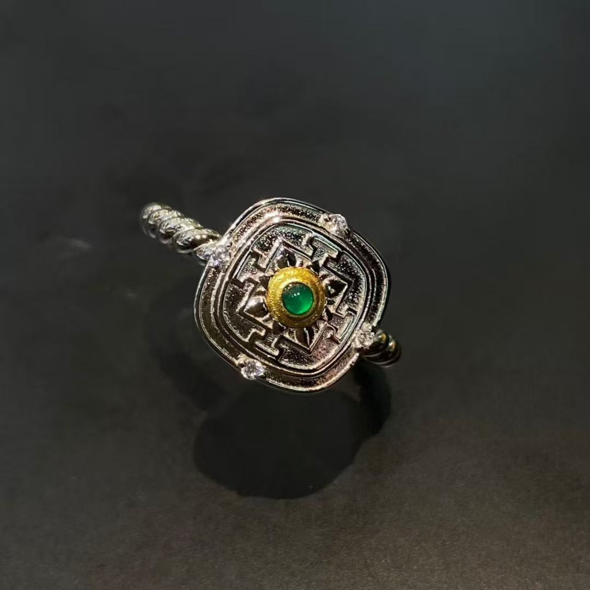 Decorative ring with a green gemstone on a dark background