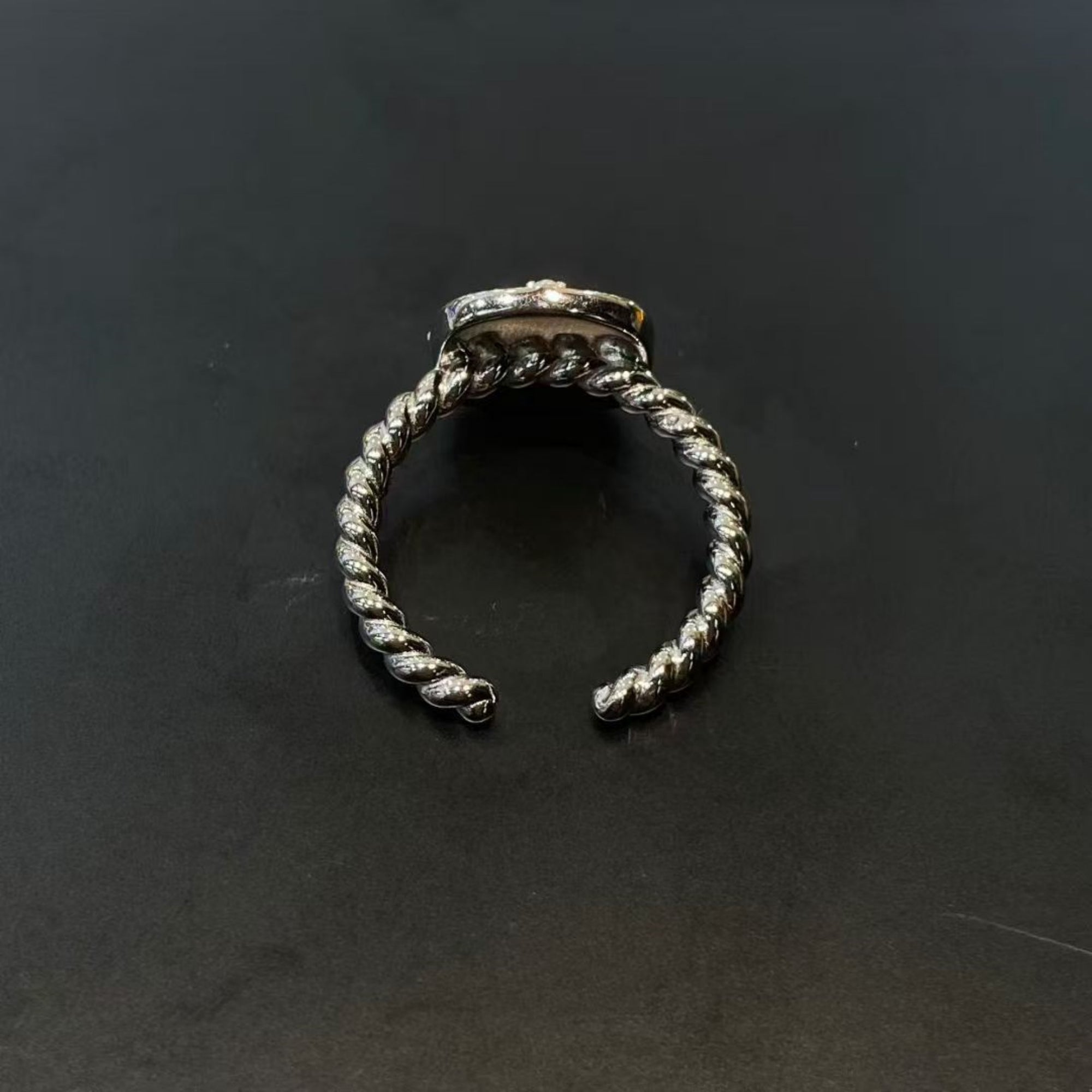 Silver ring with twisted design on a black background