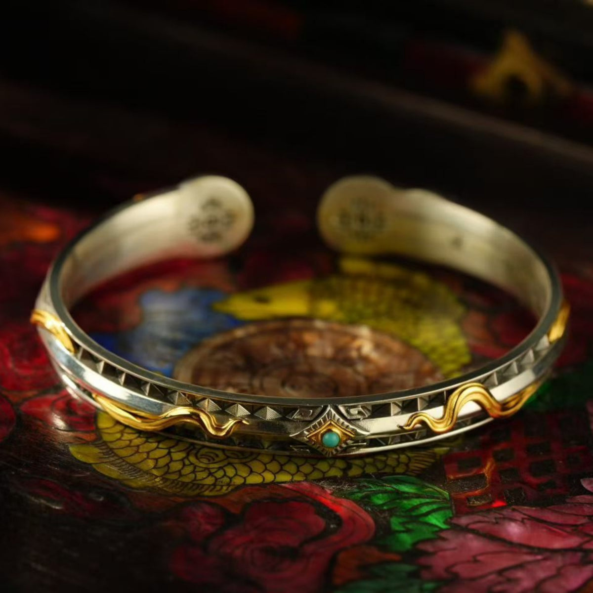Decorative bracelet with gold and silver accents on a colorful floral background