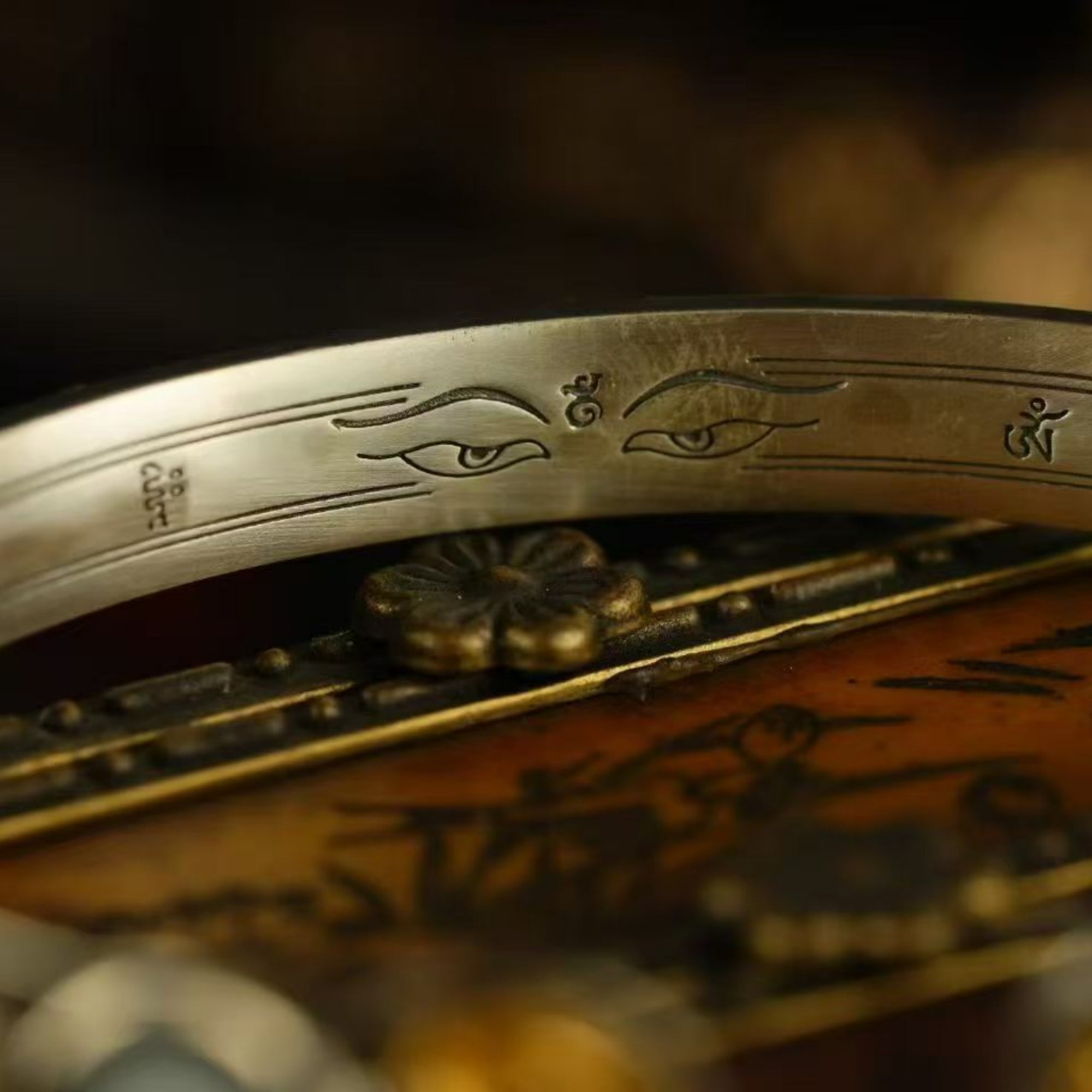 Close-up of a silver bracelet with engraved designs on a blurred background