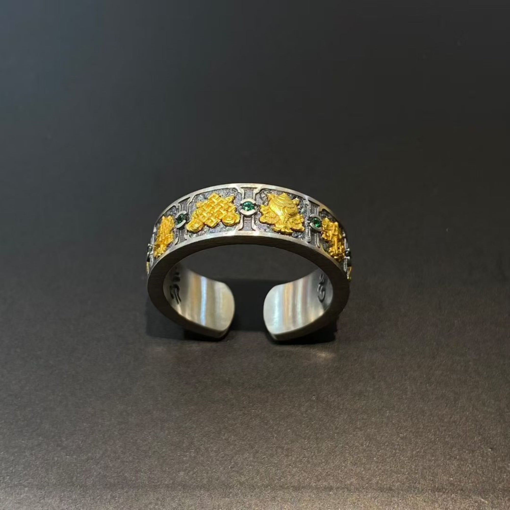 Silver ring with yellow and green gemstones on a dark background