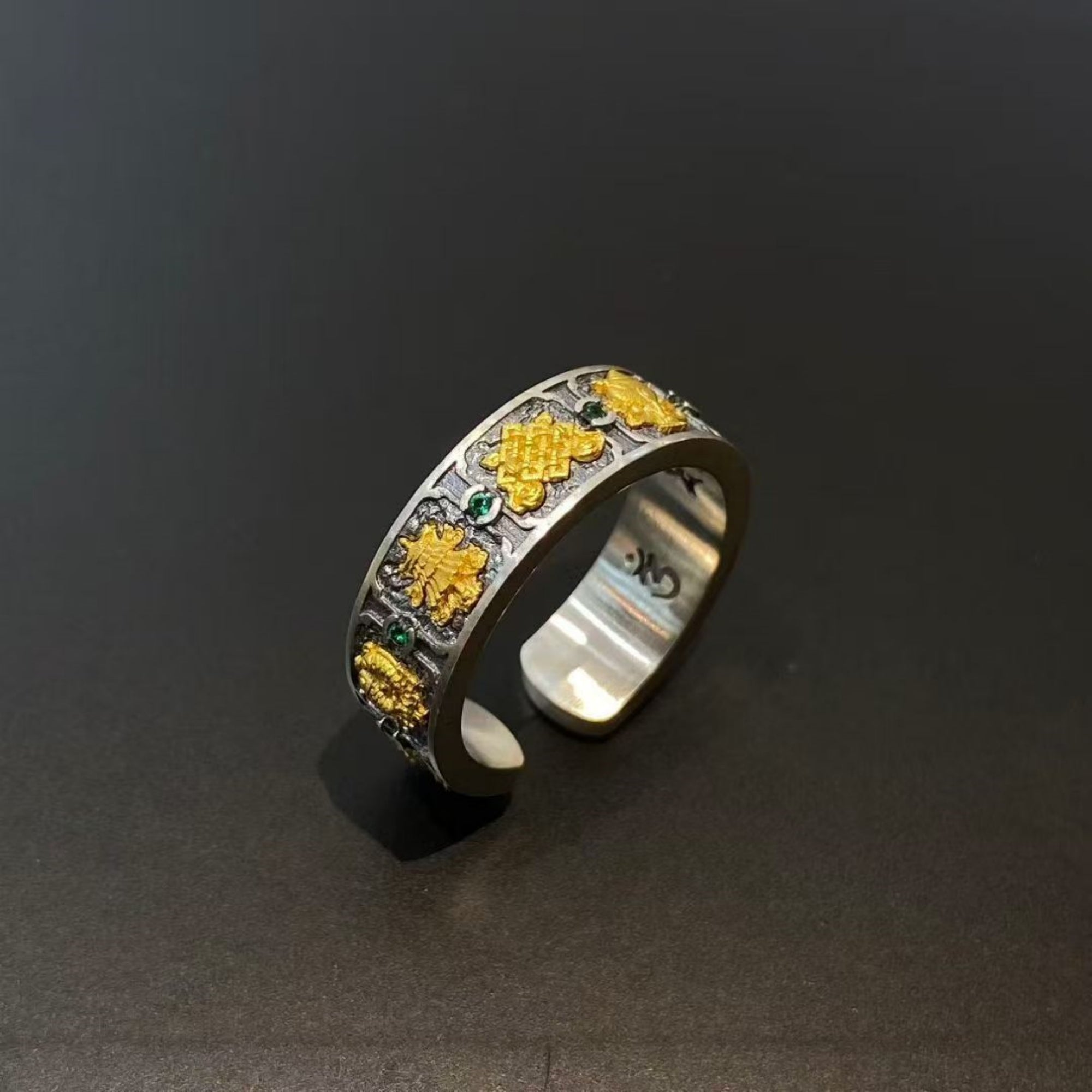 Silver ring with yellow and green gemstones on a dark background