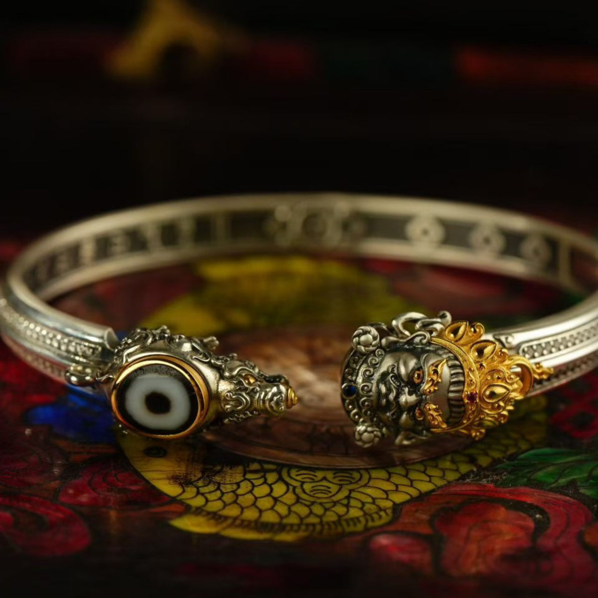 Silver bracelet with decorative elements on a colorful fabric background