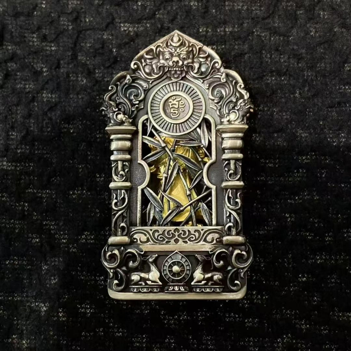 An ornate silver-toned metal religious pin depicting Saint Christopher on a bridge, set against a dark textured background.