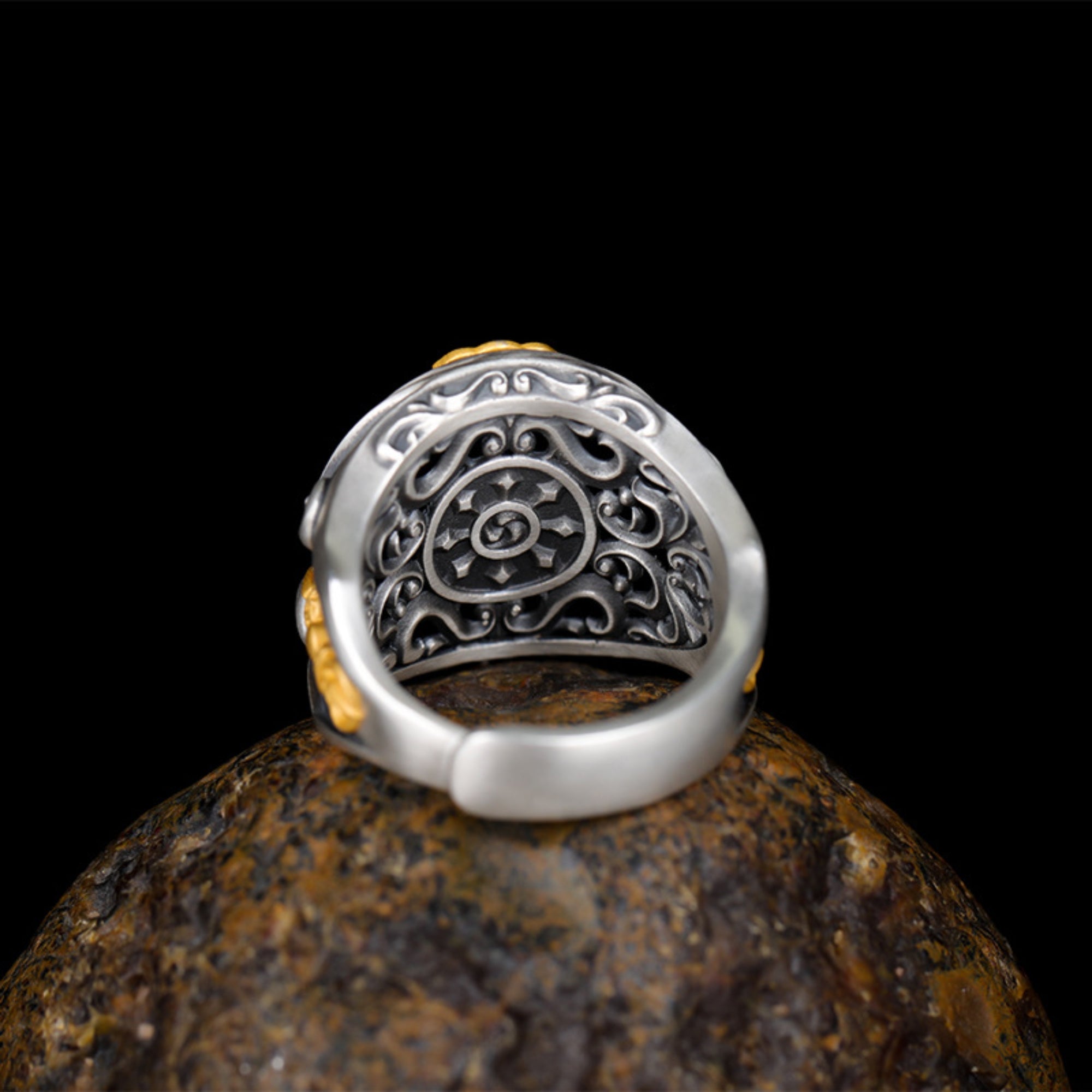 Silver ring with intricate design on a dark background